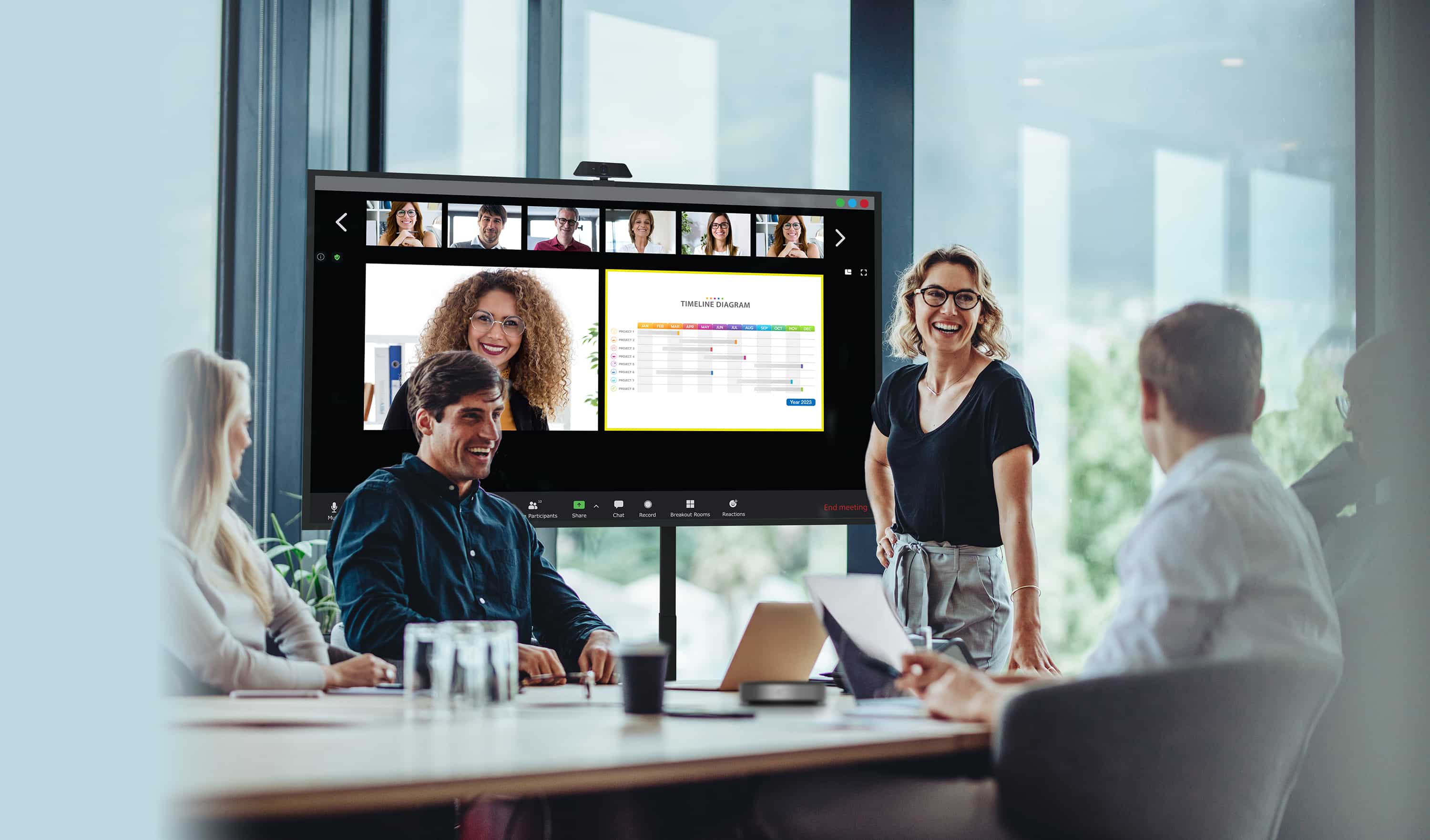 Business people conducting a meeting with some staff physically present looking at an Optoma N-Series display whilst their remote colleagues are shown on screen alongside the content they are sharing.